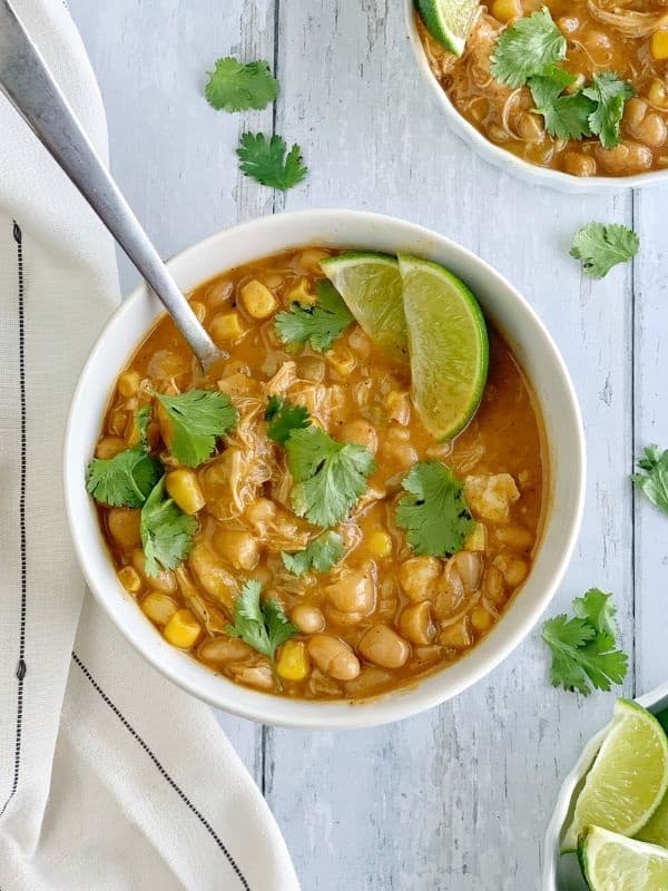 coconut lime white bean chicken chili with lime wedges and cilantro