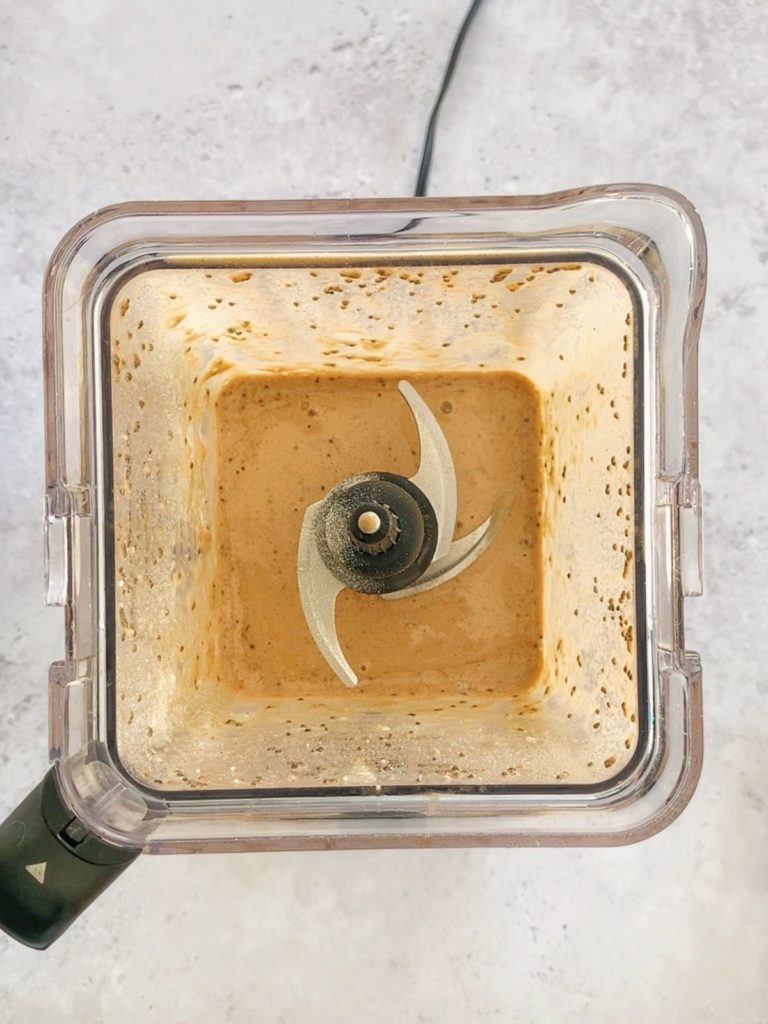 A blended coffee protein shake in the bottom of a blender.