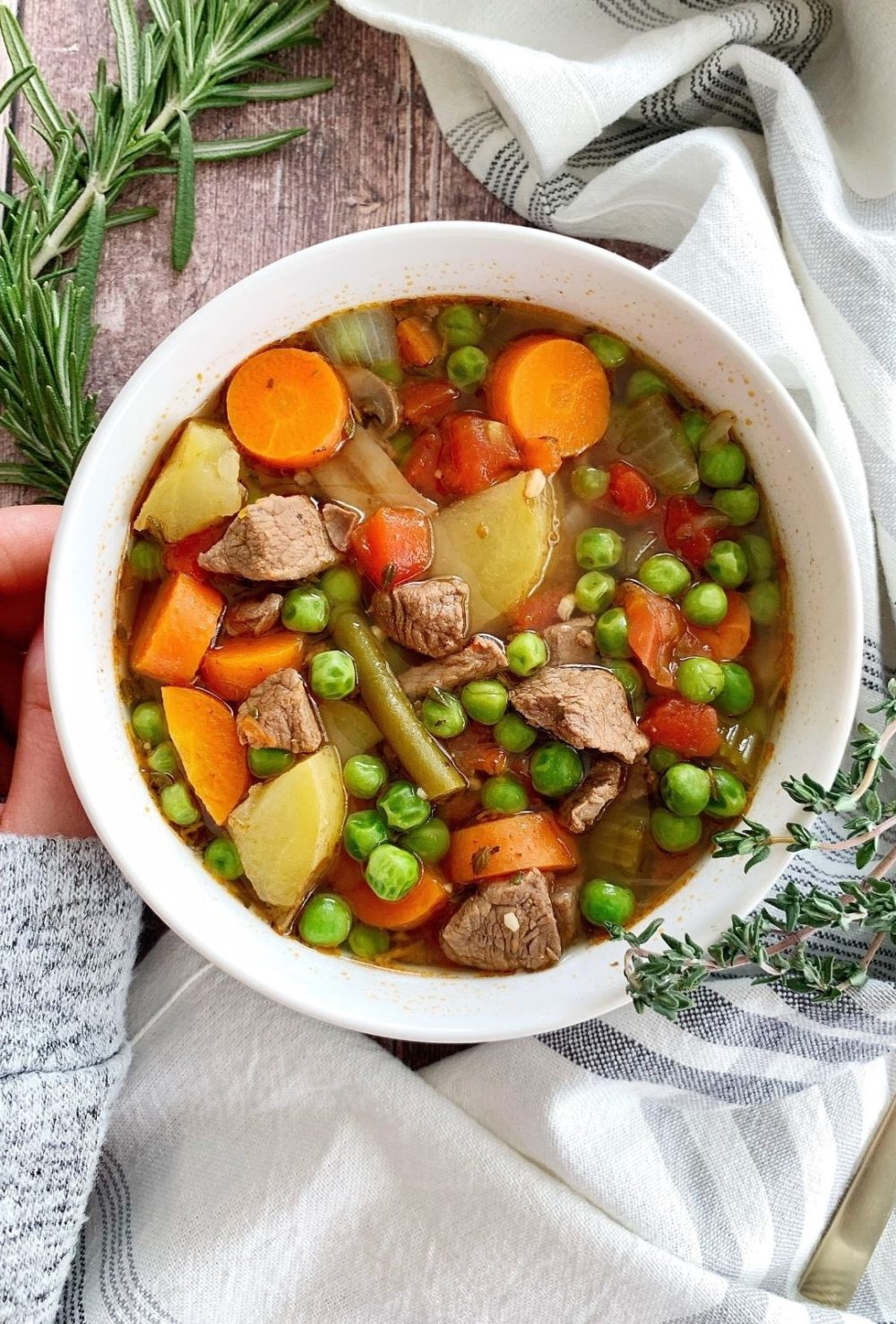 A bowl of Instant Pot beef vegetable soup with rosemary and thyme.