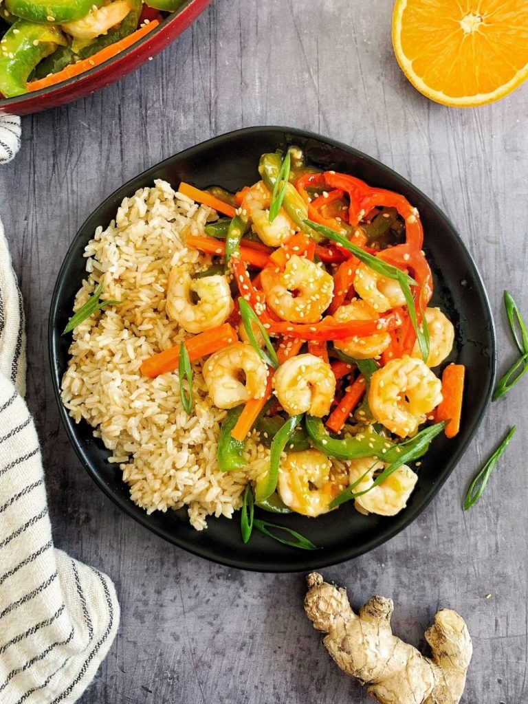 A plate with honey orange shrimp, stir fry vegetables, and rice.