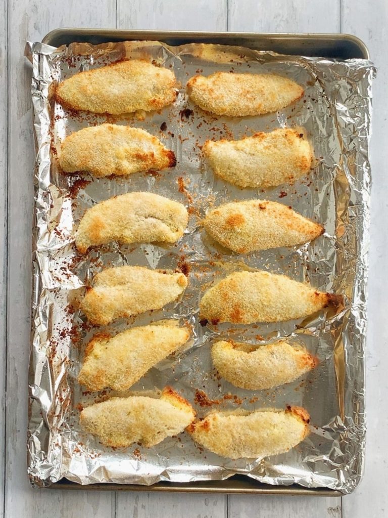 A sheet pan with golden baked coconut crusted chicken