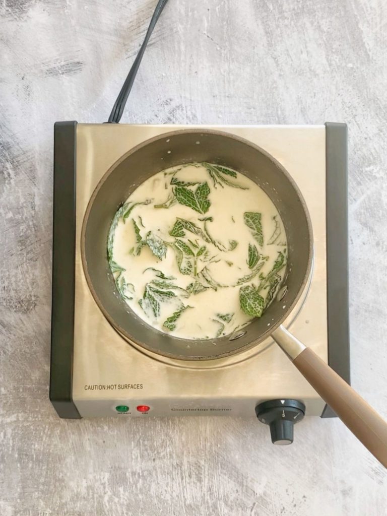 A pot with coconut milk, whipping cream, and fresh mint leaves.