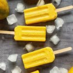Three mango popsicles surrounded by ice.