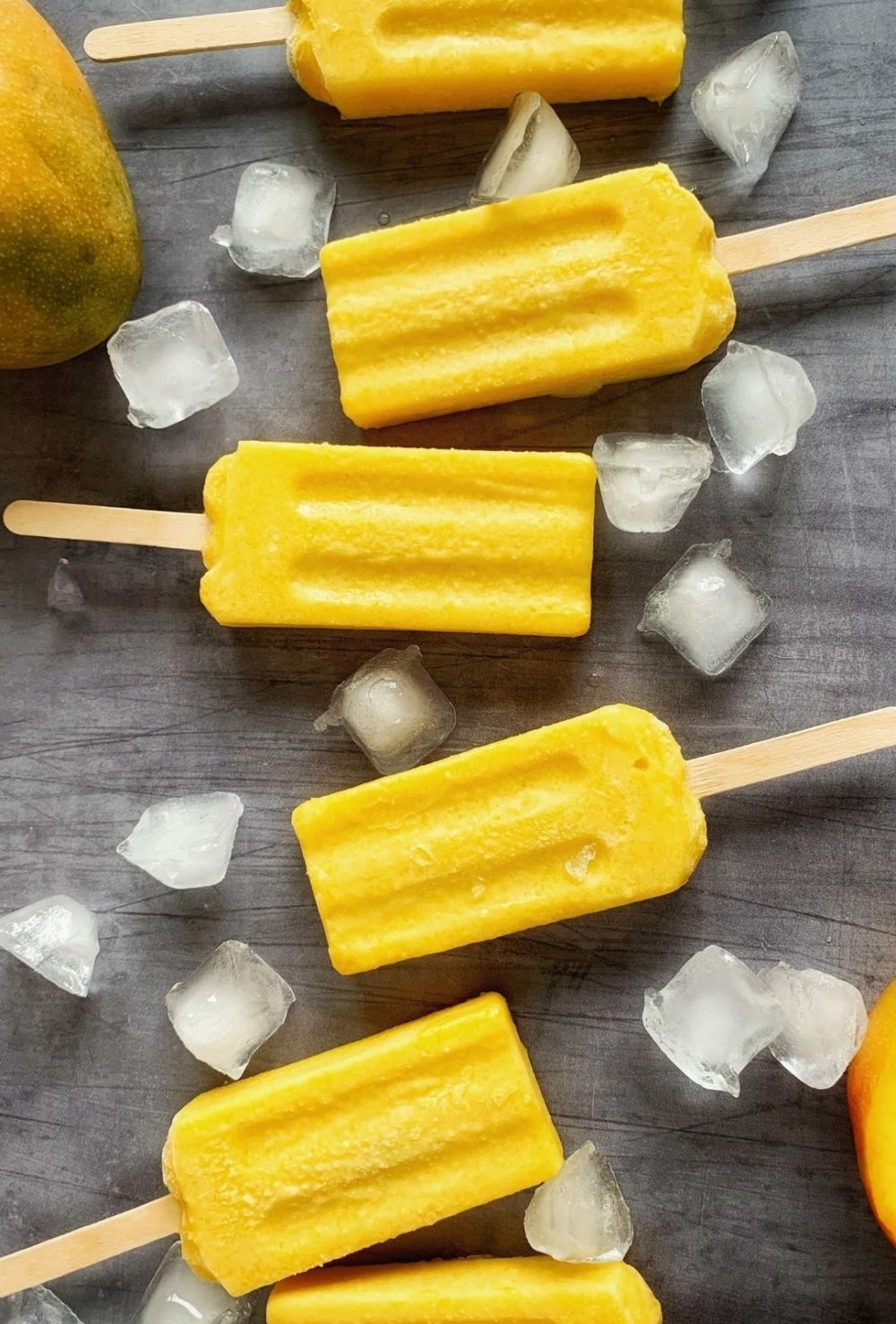 Several mango popsicles surrounded by ice.