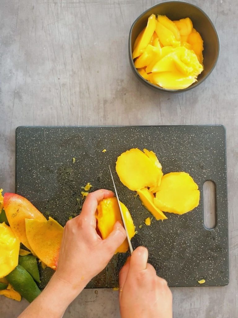 Fresh mangoes being sliced on a cutting board.