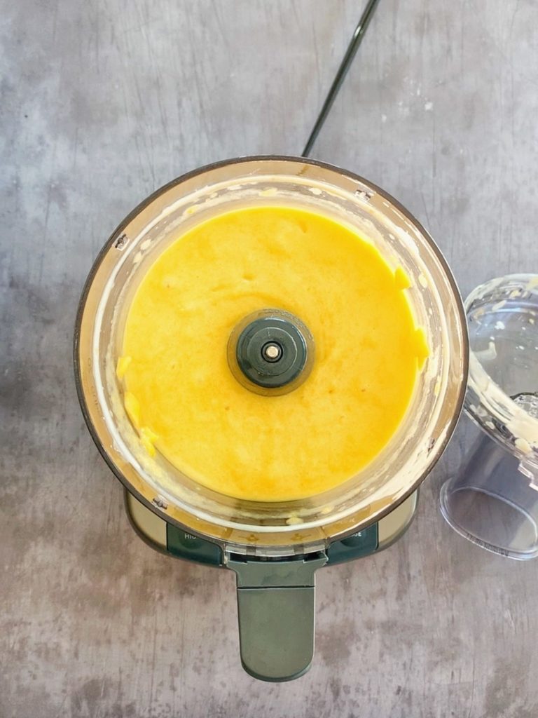 The ingredients for mango popsicles pureed together in a food processor.