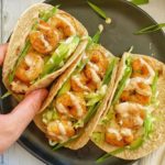 Three spicy shrimp tacos on plate.