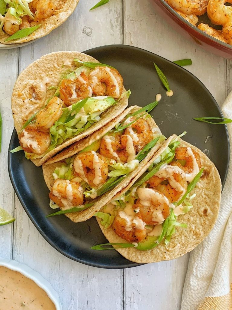 Three spicy shrimp tacos on a plate.