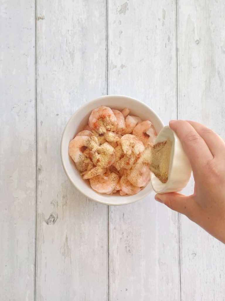 A bowl of shrimp being seasoned.