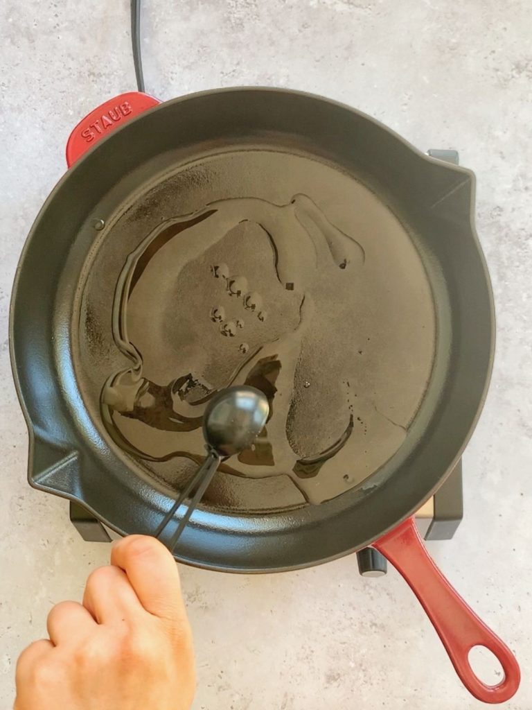 A skillet with sesame oil being drizzled into it.