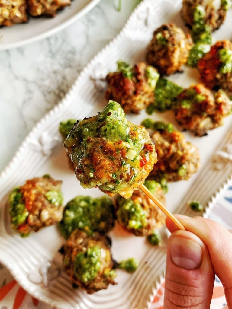 A homemade meatball dipped in chimichurri sauce.