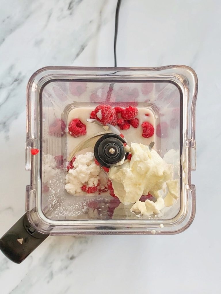 The ingredients for the raspberry smoothie in a blender.