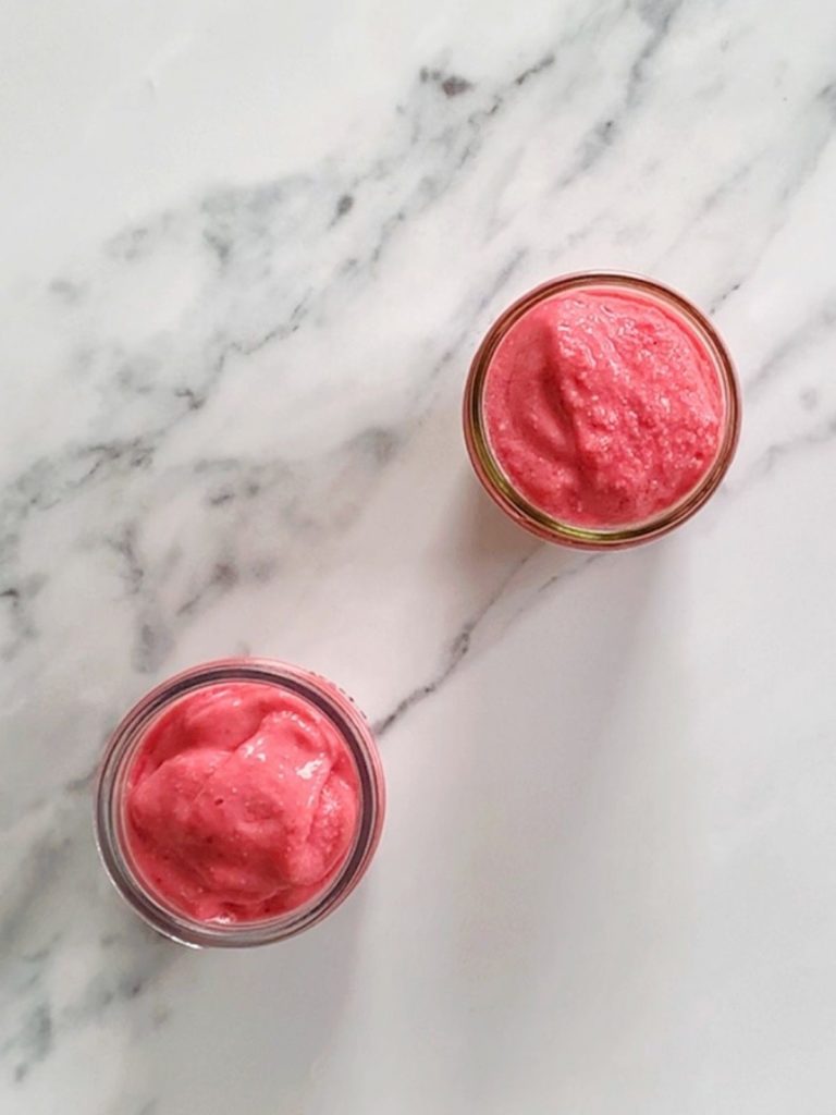 Two raspberry smoothies in glass jars.