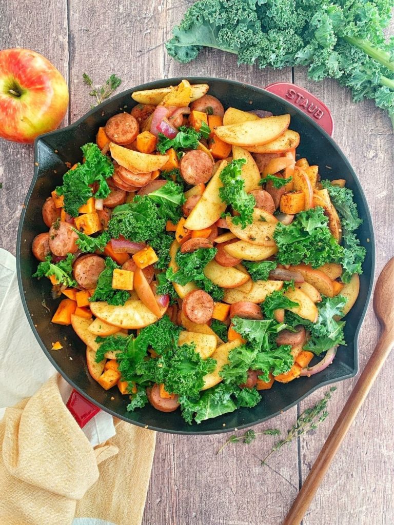 A skillet full of apples, sweet potatoes, kale, and chicken apple sausage.