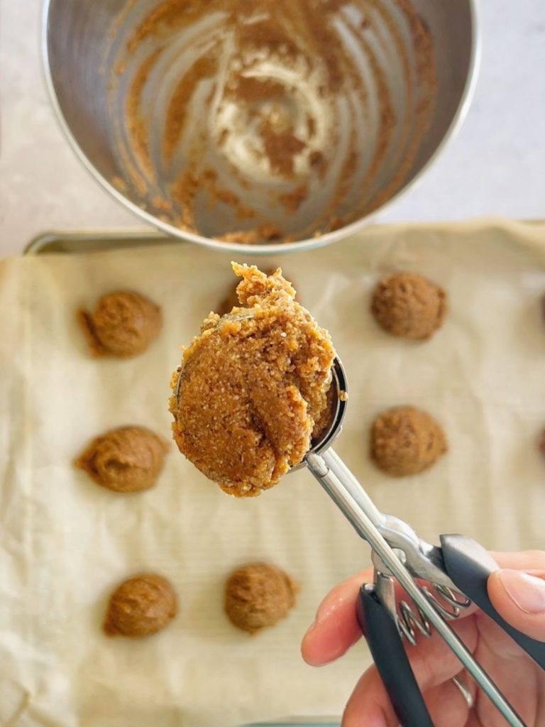 A cookie dough scoop full of almond flour peanut butter cookie dough.