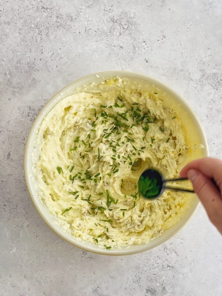 The whipped Boursin potatoes being topped with fresh chives.