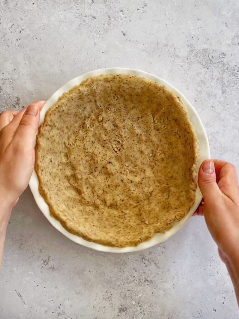The pie crust dough spread evenly in a pie pan.
