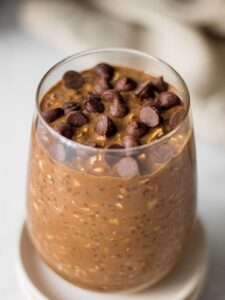 A glass of chocolate overnight oats topped with chocolate chips.