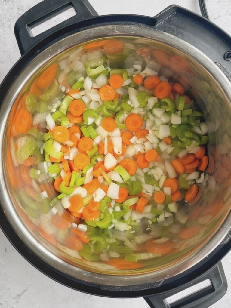 Carrots, celery, onions, and garlic sauteeing in the Instant Pot.