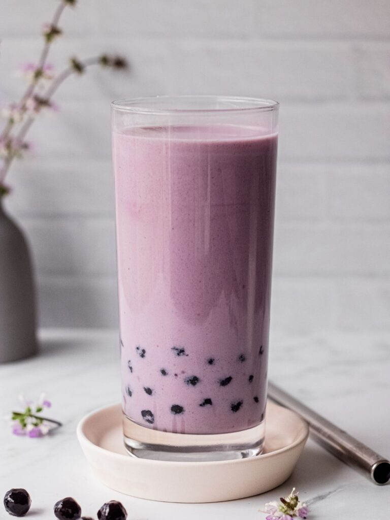 A glass of taro milk tea with boba pearls.