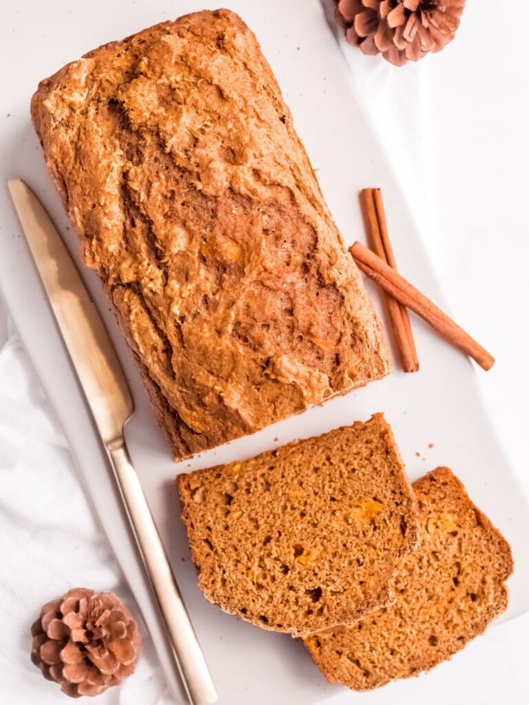 A loaf of butternut squash bread partially sliced on a cutting board.