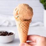 hand holding a sugar cone topped with a single scoop of homemade coffee ice cream.