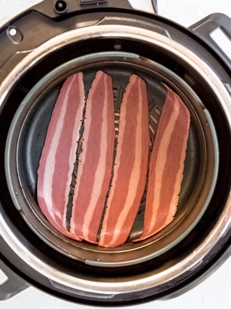 4 slices of raw turkey bacon in the air fryer basket.