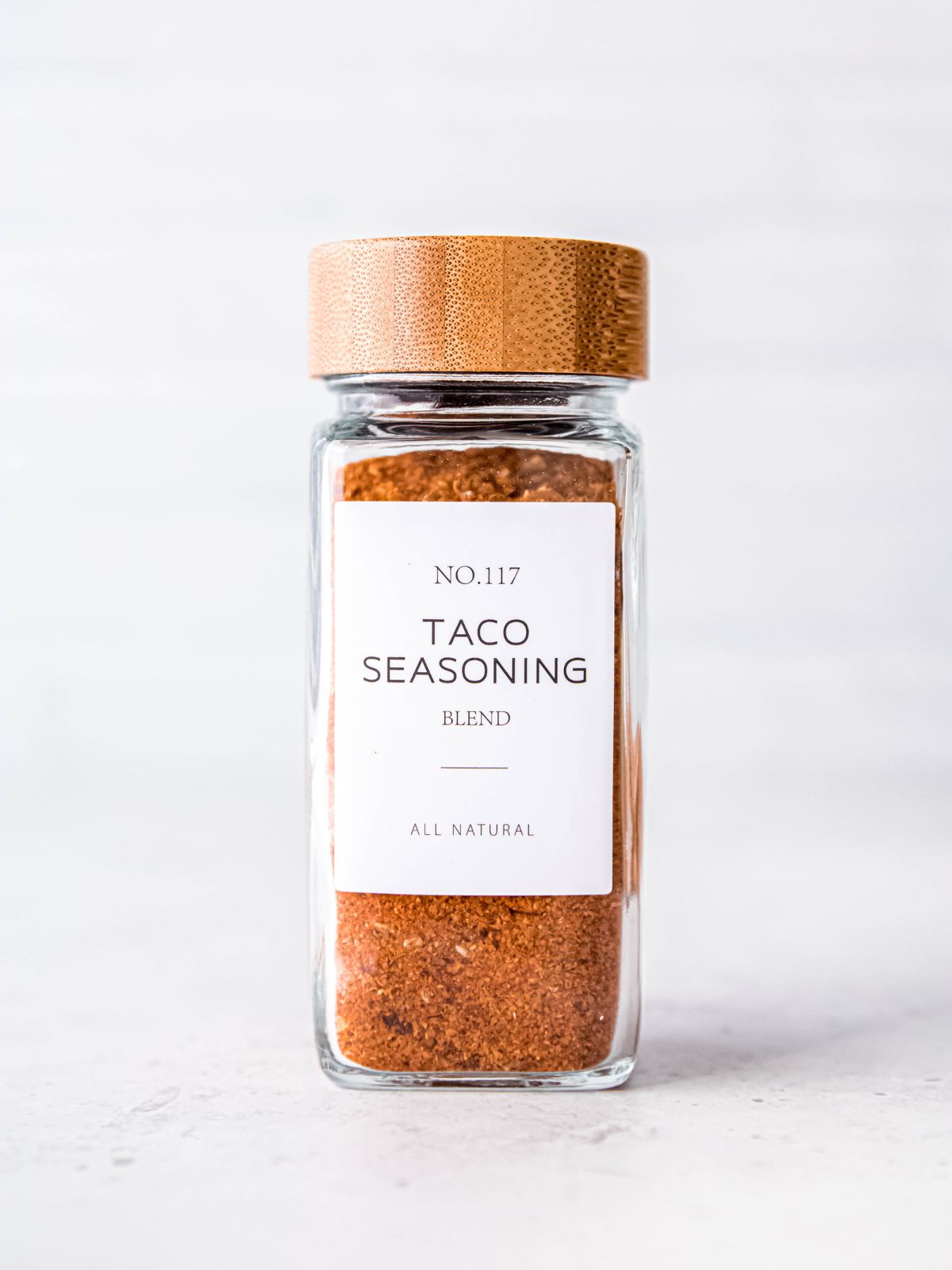 closeup shot of salt-free taco seasoning blend in a cute glass jar with a wooden lid.