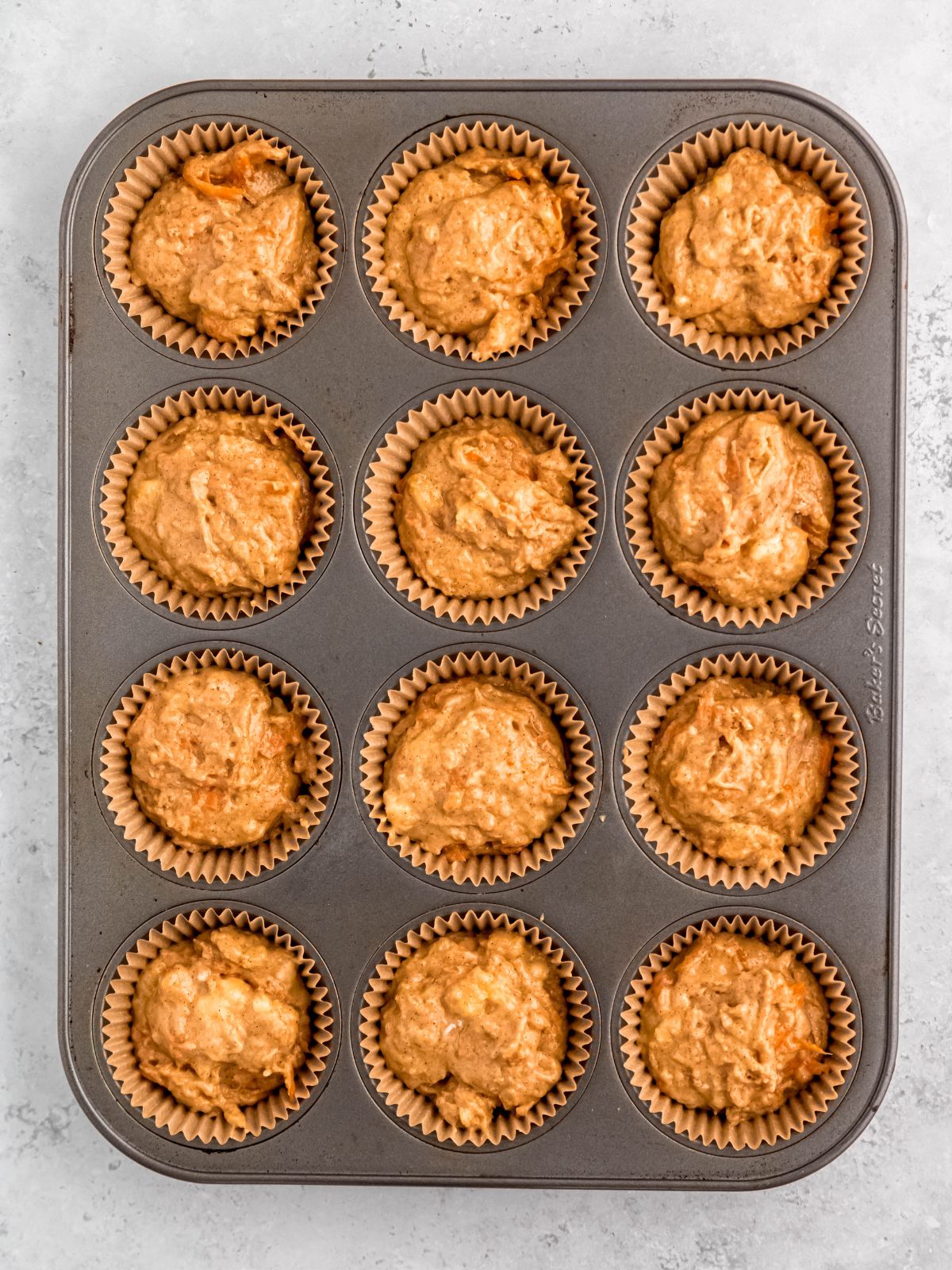 step 4: banana carrot muffin batter divvied up into lined muffin tin for baking.