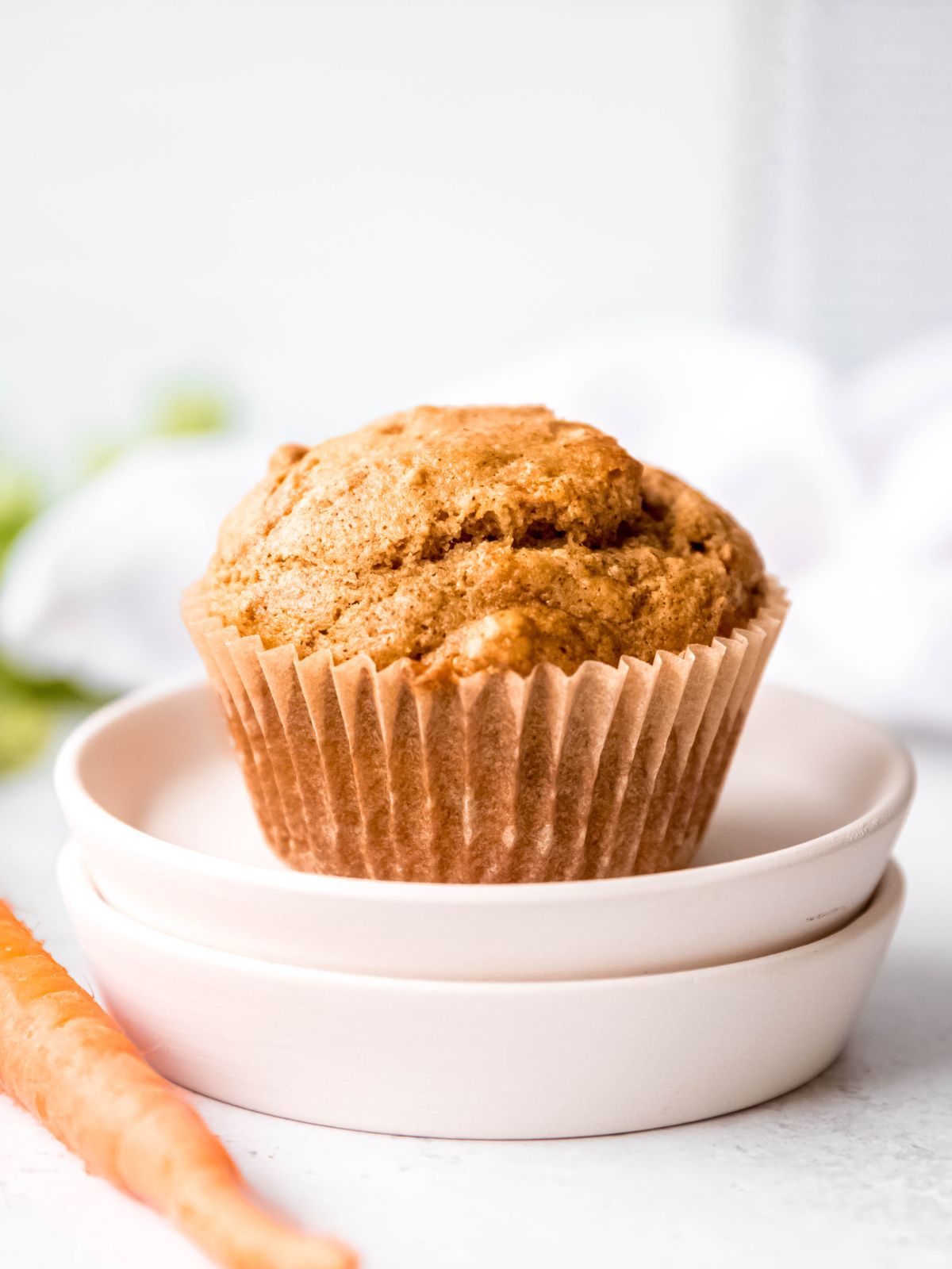 closeup shot of a banana carrot muffin on a stack of small white plates.