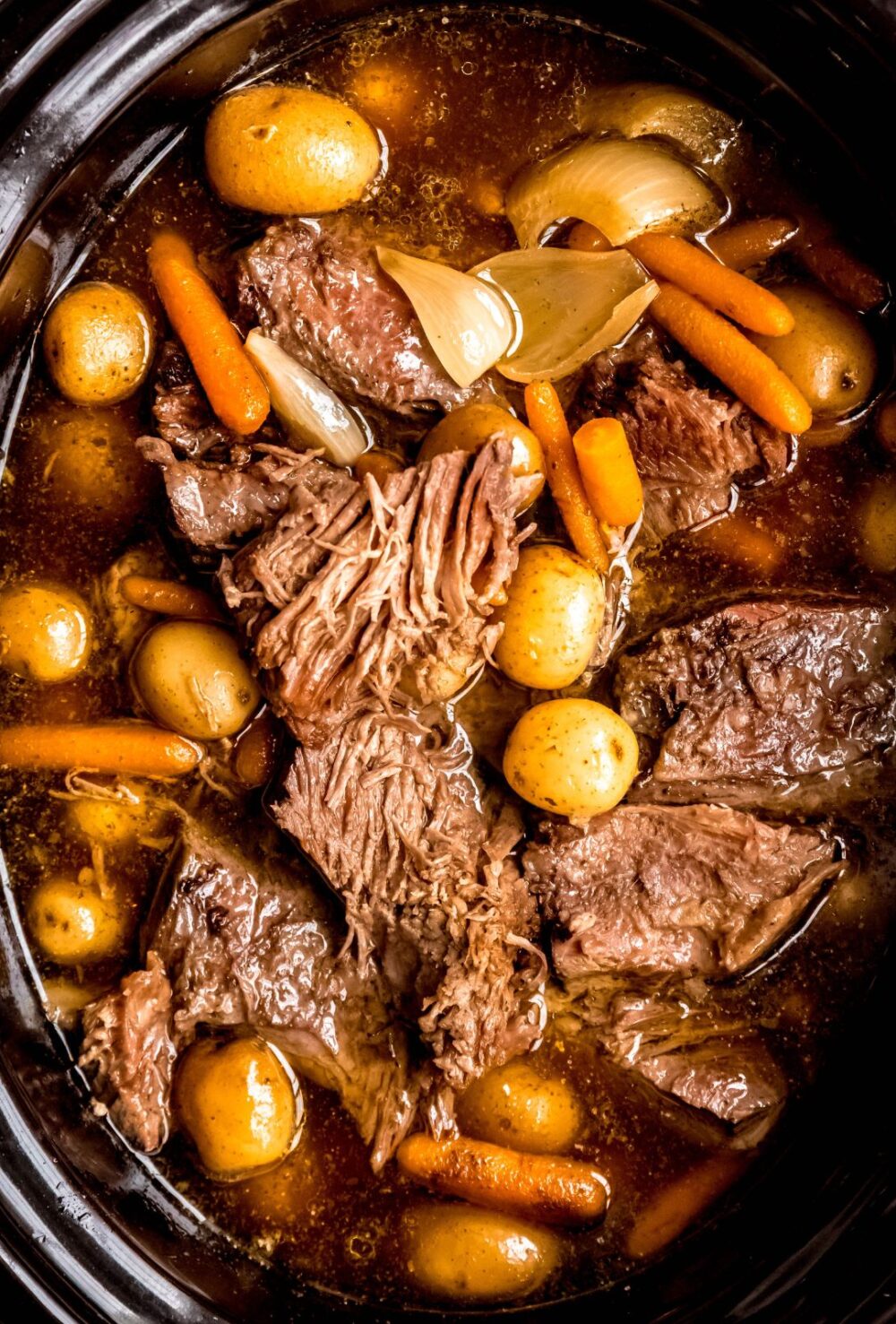 closeup overhead shot of bottom round rump roast with root vegetables in the crockpot.