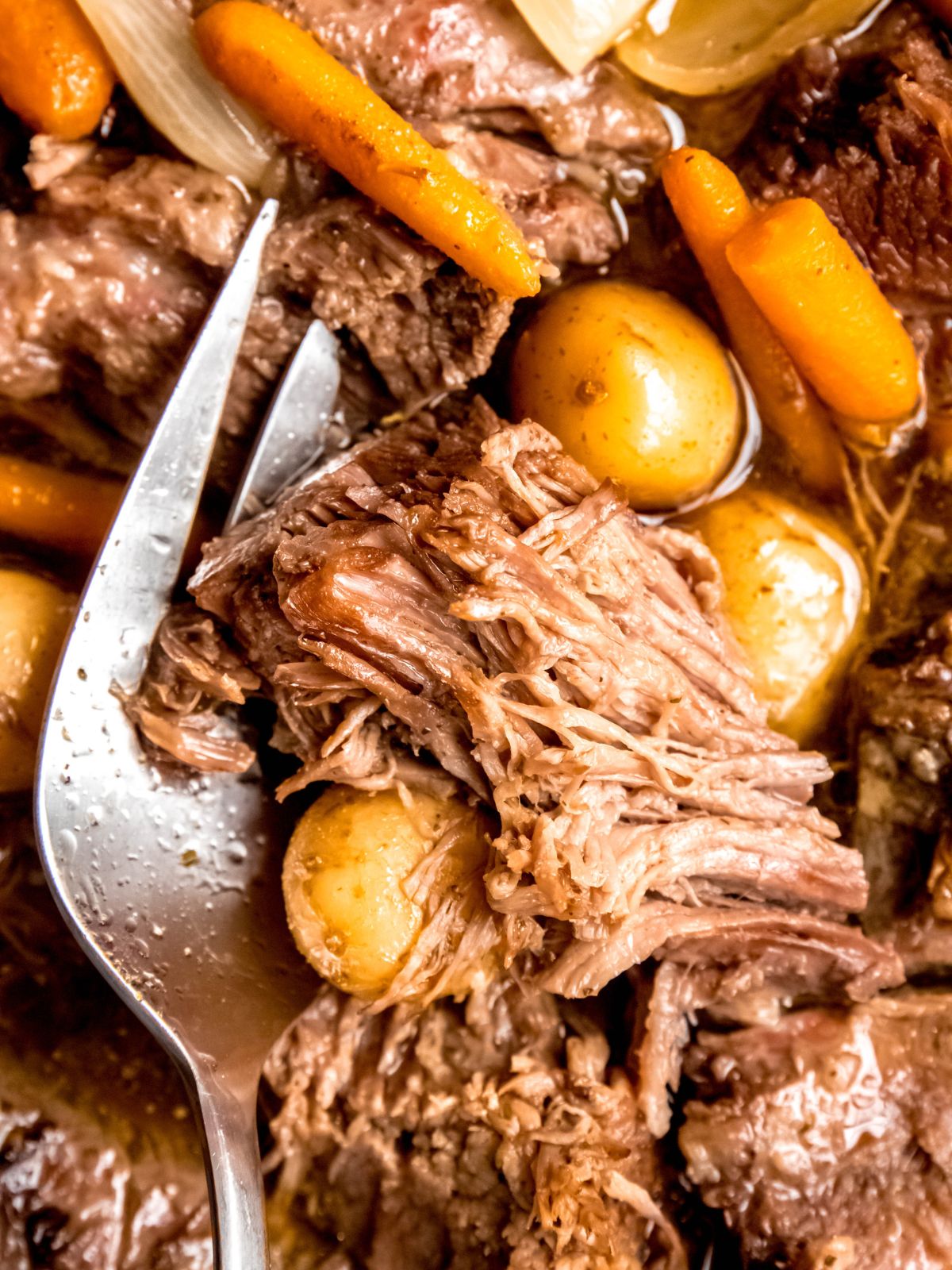 serving fork in a pile of crockpot bottom round rump roast.