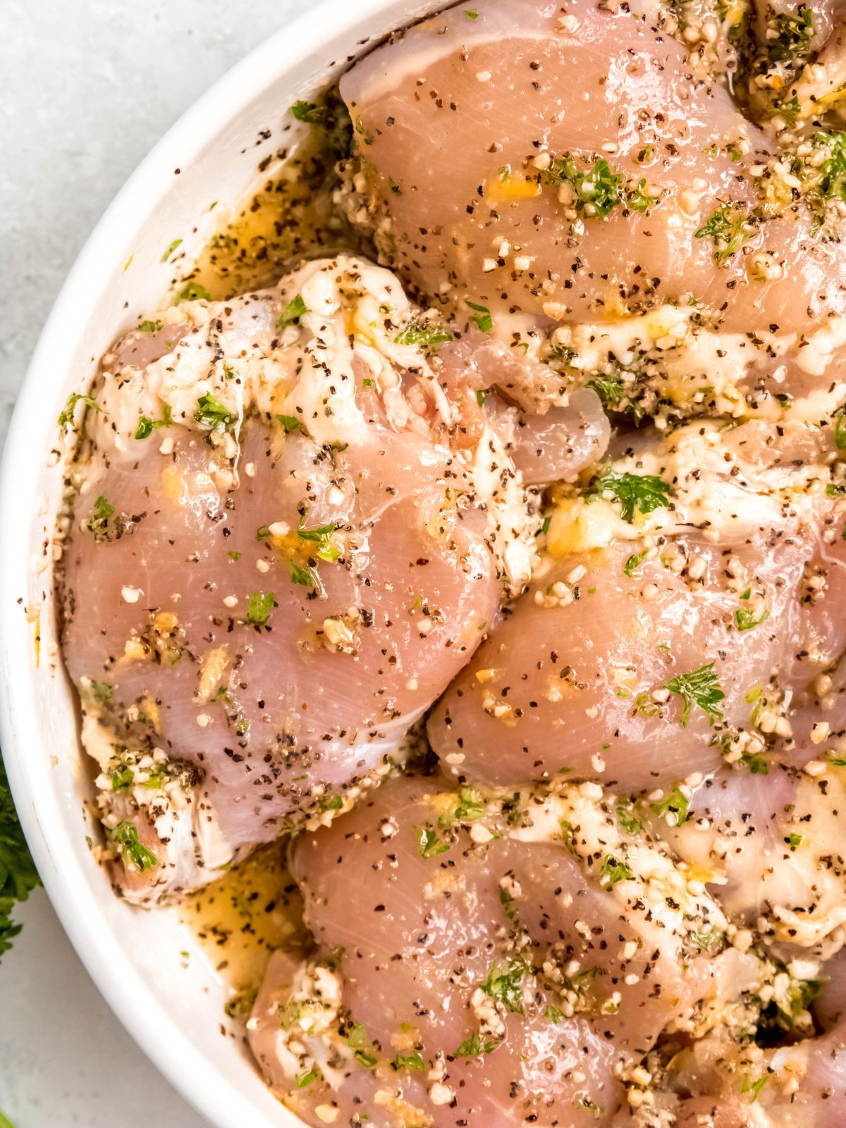 closeup shot of raw chicken marinating in a bright and citrusy lemon pepper marinade.