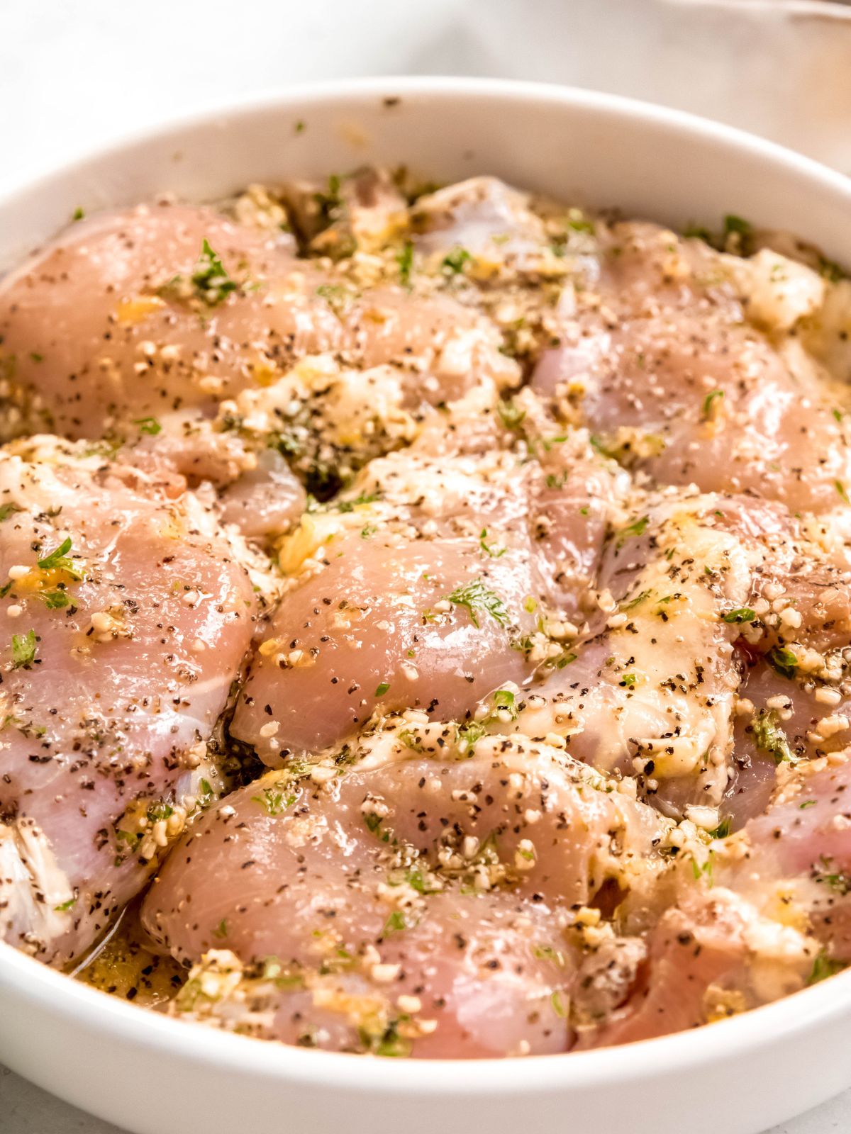 45 degree angle shot of chicken thighs marinating in lemon pepper marinade.