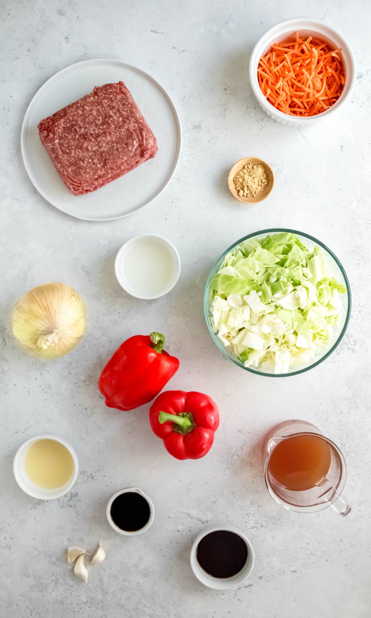 All of the ingredients for cabbage and ground beef stir-fry on a gray background.