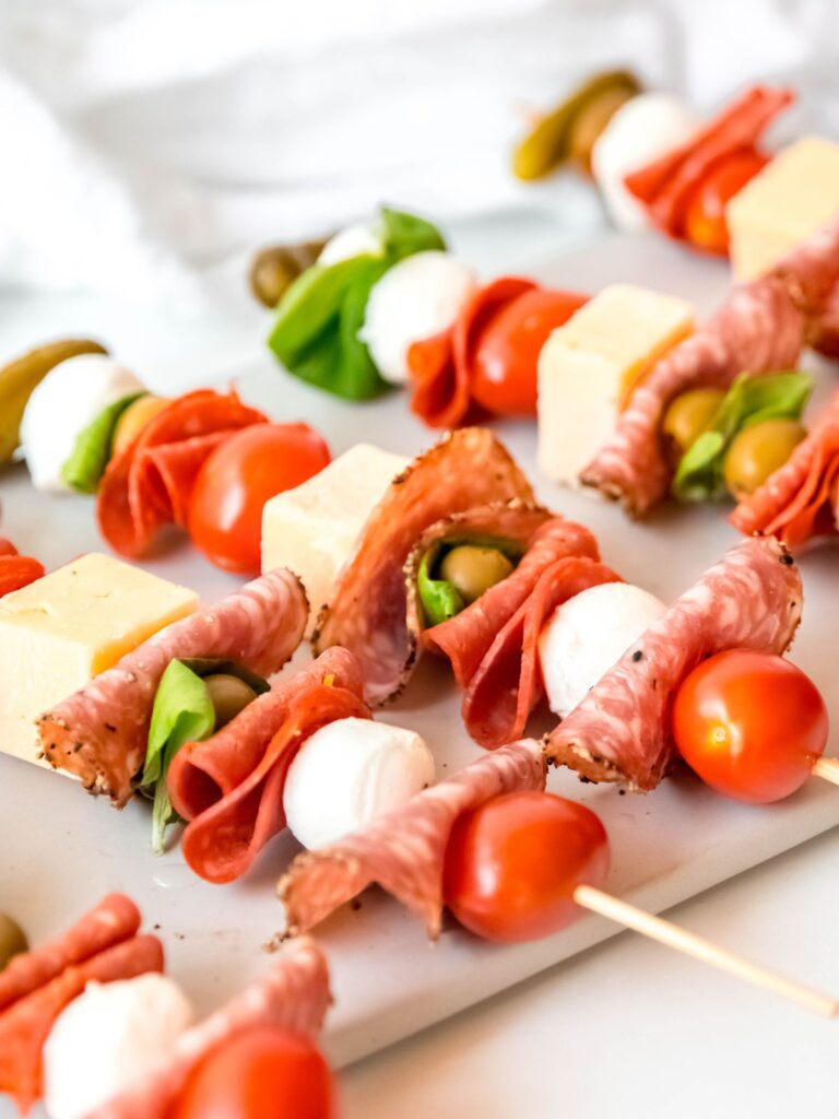 meat and cheese charcuterie sticks with olives, tomatoes, and basil layered in.