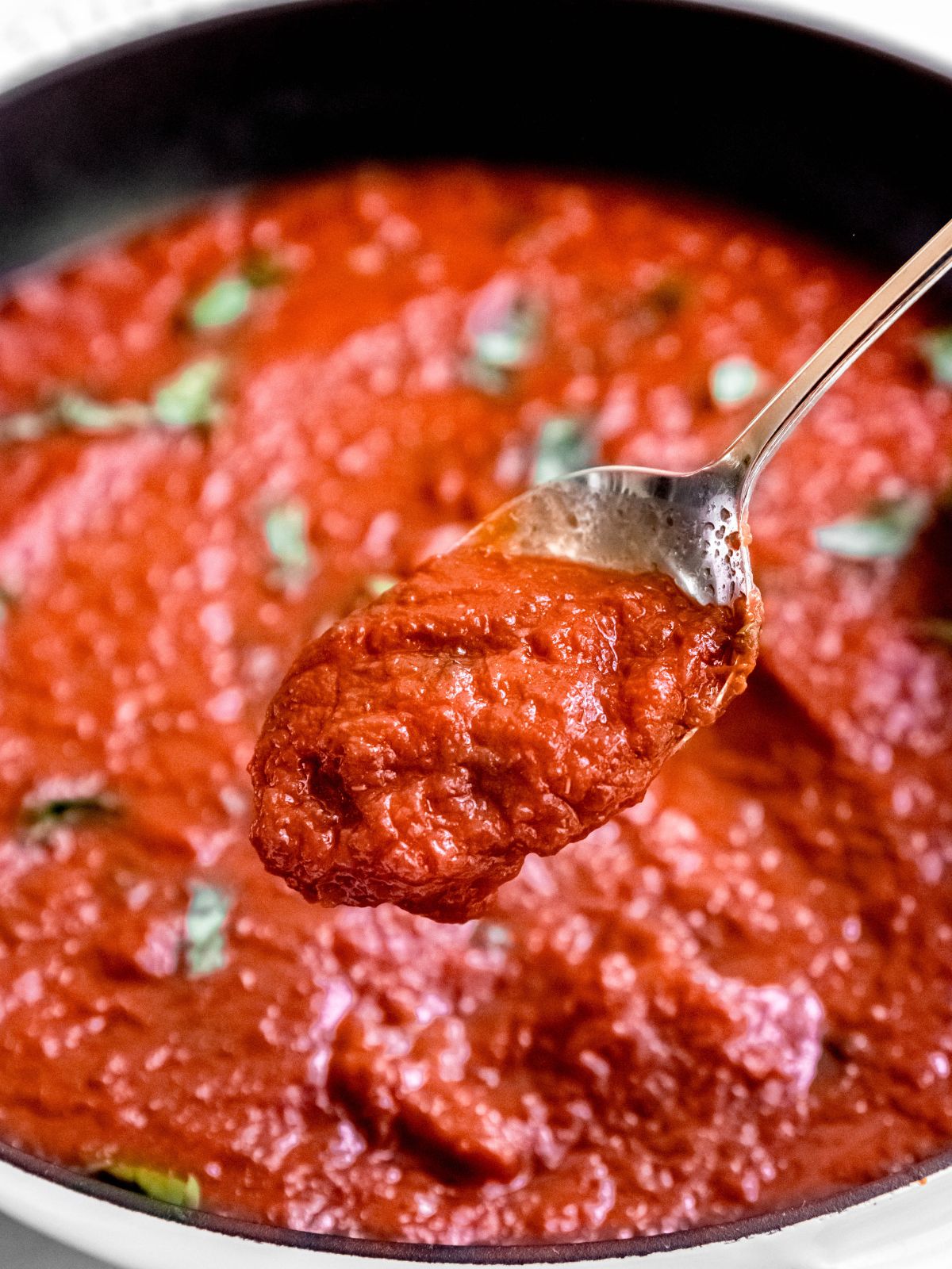 closeup shot of a spoonful of homemade marinara sauce showing how thick and hearty it is.