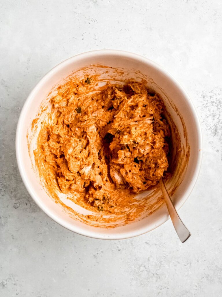 A bowl of buffalo chicken before scooping into the zucchini halves.