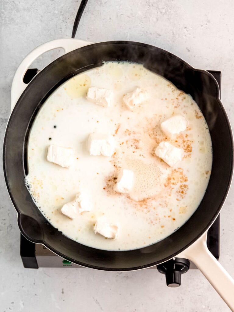 A skillet of milk and cream cheese.