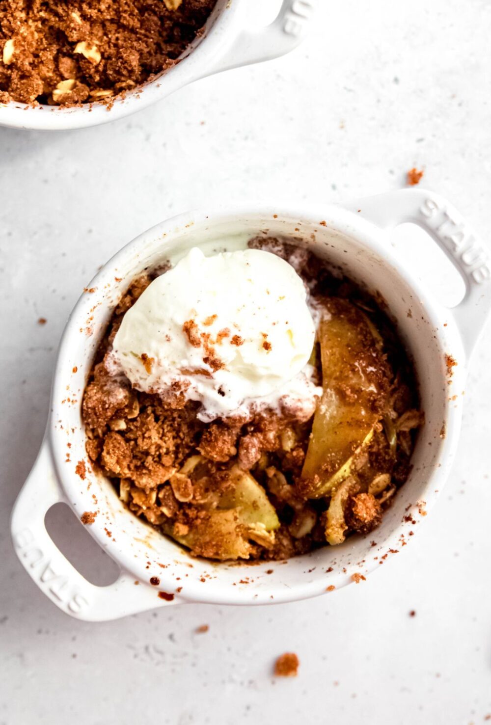 Overhead shot of a small dish of air fryer apple crisp with a small scoop of ice cream.
