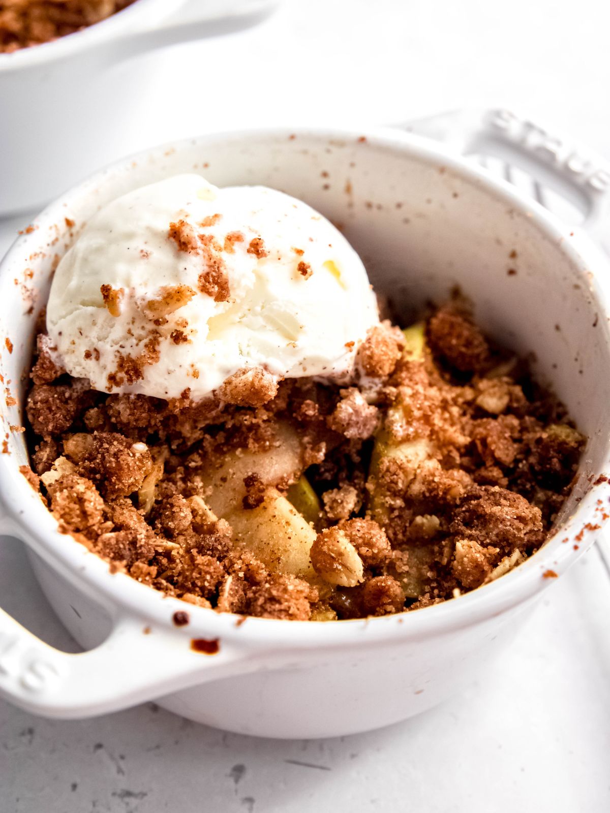 Angled shot of a dish of air fryer apple crisp with a scoop of ice cream.