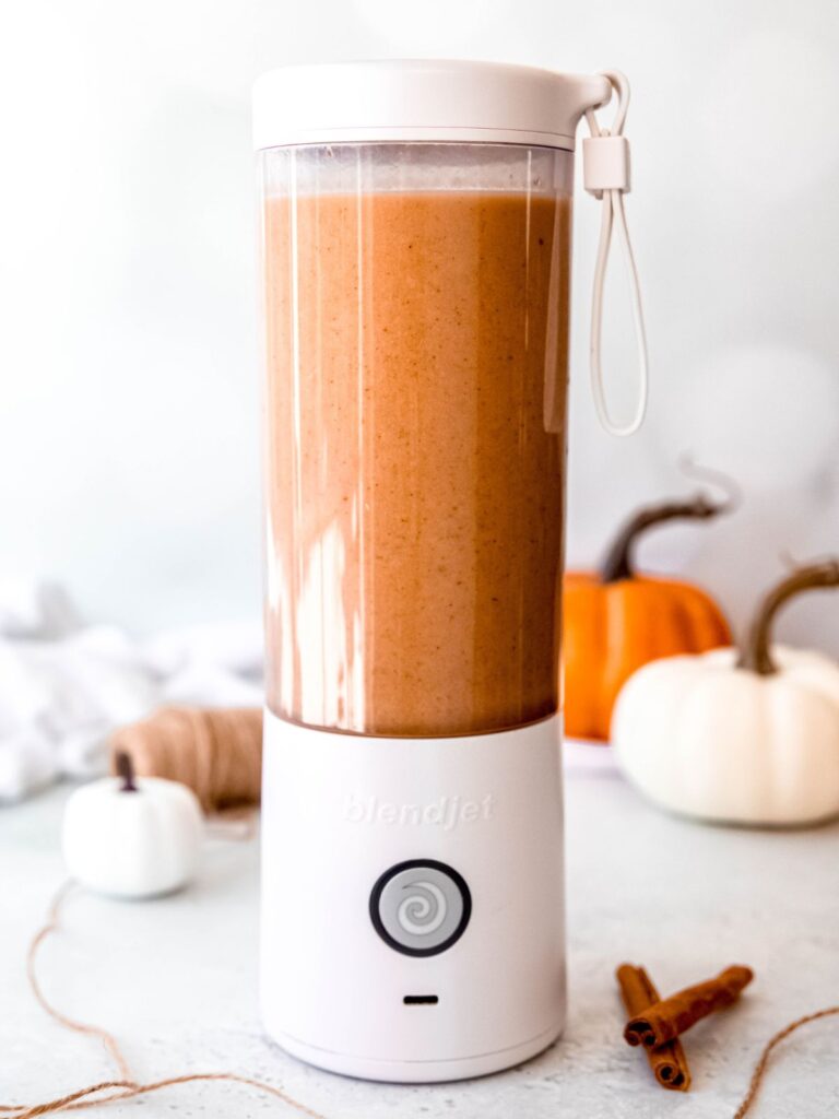 action shot of pumpkin protein shake being blended in the portable blender.