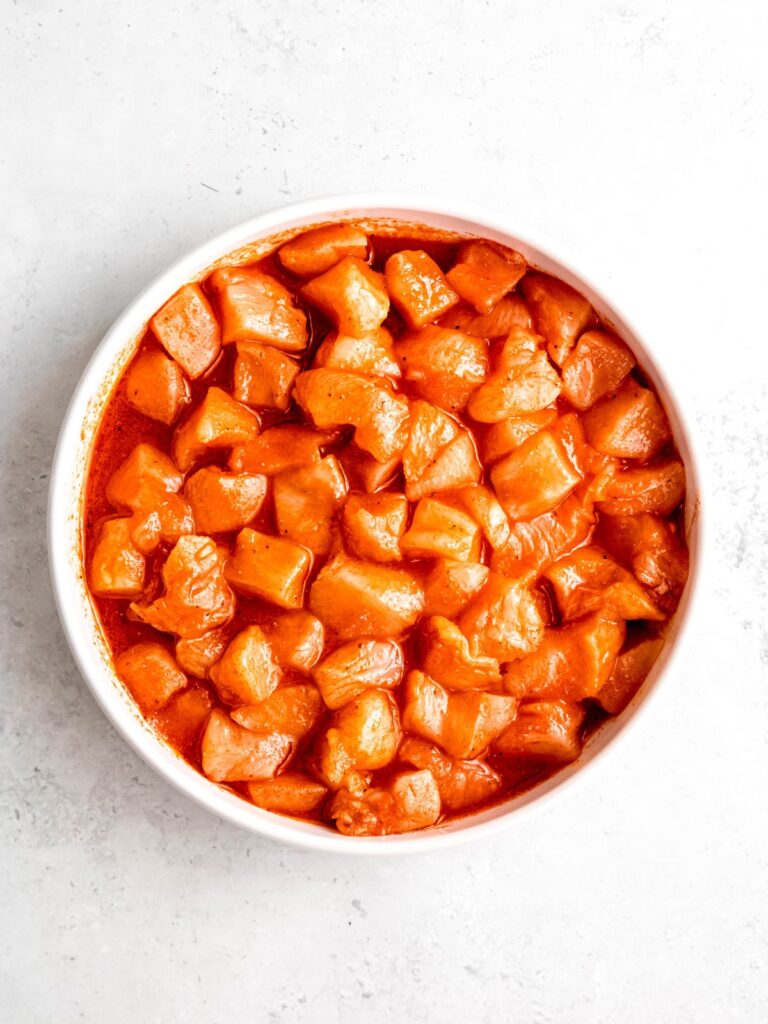 cubed chicken pieces added to the bowl with the marinade and tossed to coat.