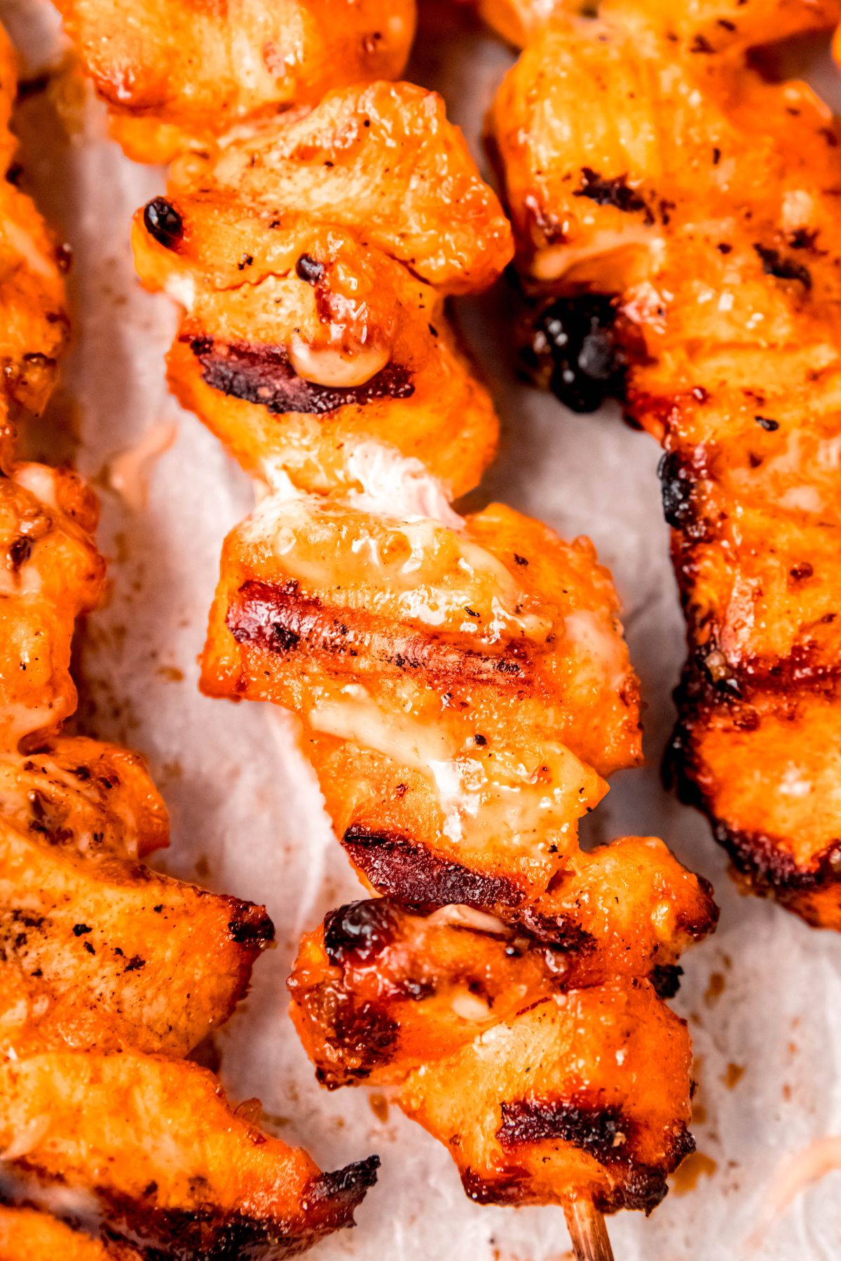hyper closeup overhead shot of a grilled bang bang chicken skewer with beautiful char marks from the grill.
