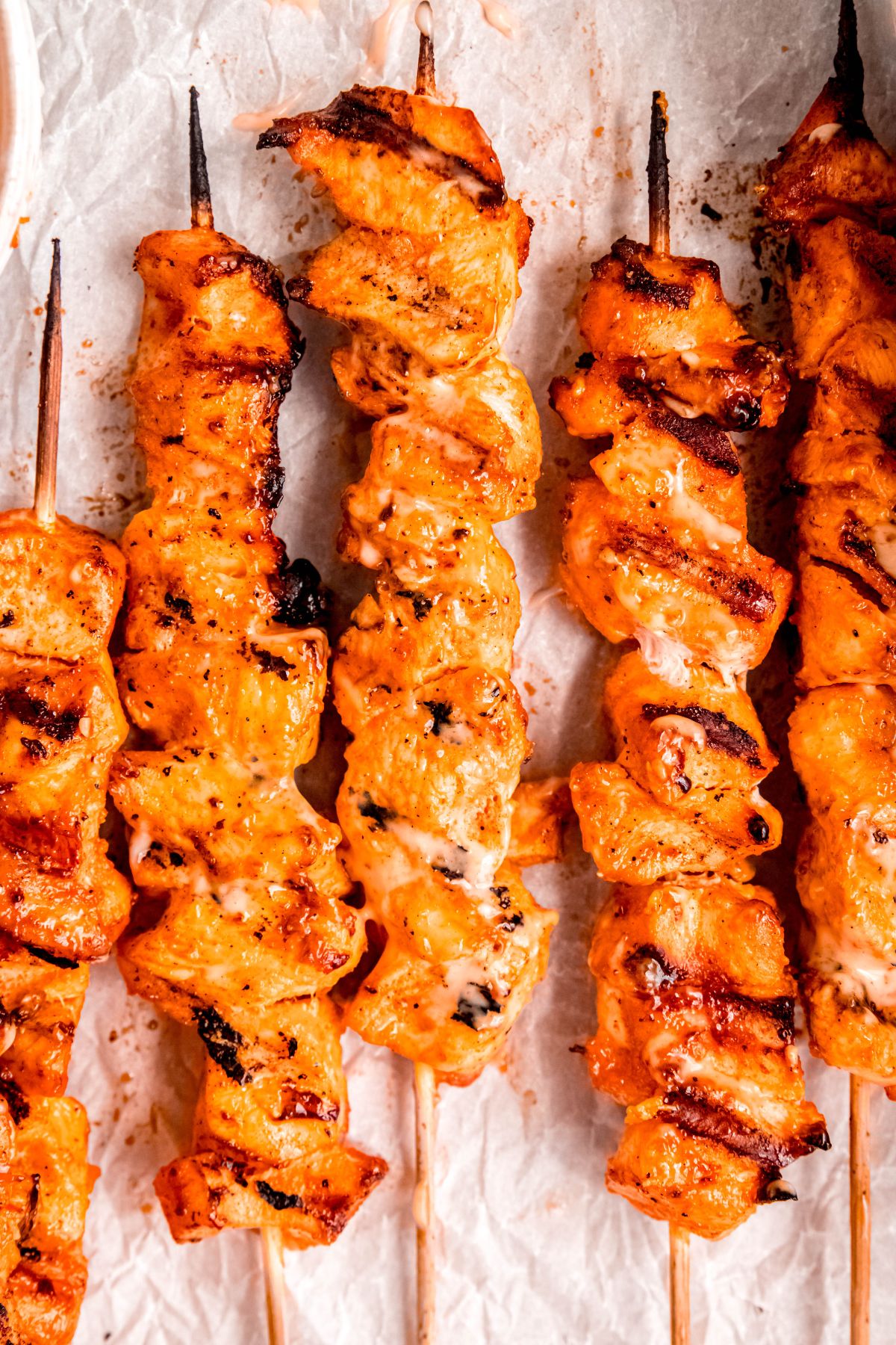 closeup shot of homemade bang bang chicken skewers after grilling; you can still see the mayo based sauce being creamy in some spots.