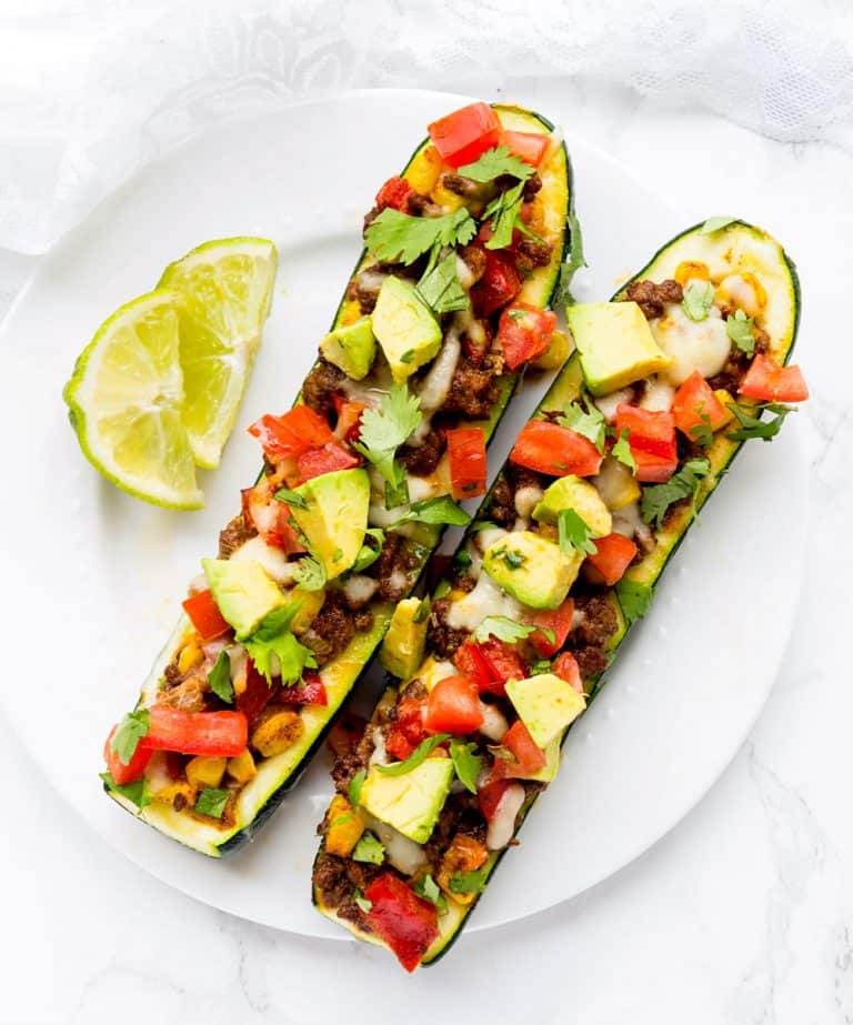 An overhead shot of two enchilada stuffed zucchini boat on a white plate.