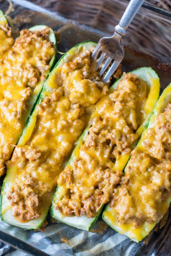 An overheaad shot of cheeseburger stuffed zucchini boats in a glass pan.