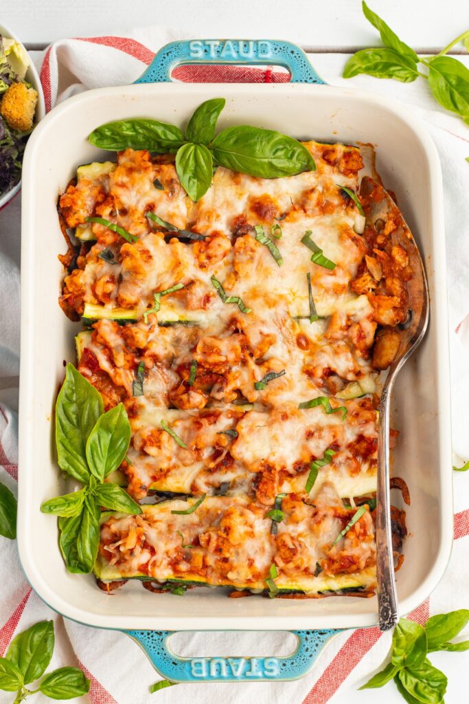 An overhead shot of a white pan of chicken zucchini boats.