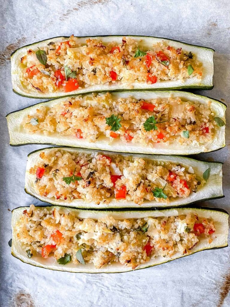 An overhead shot of quinoa-stuffed zucchini boats on a white background.