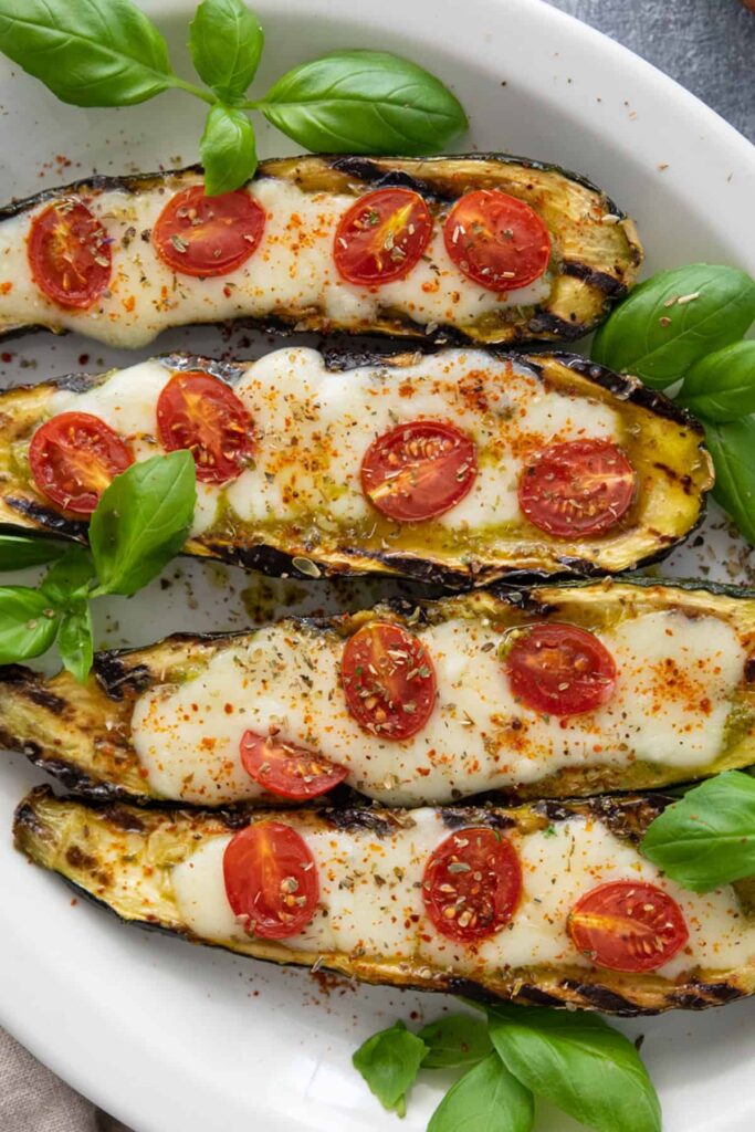 An overhead shot of 4 caprese stuffed eggplant in a white dish.